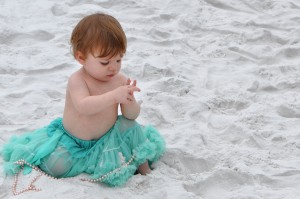 baby in green tutu with sandy hands